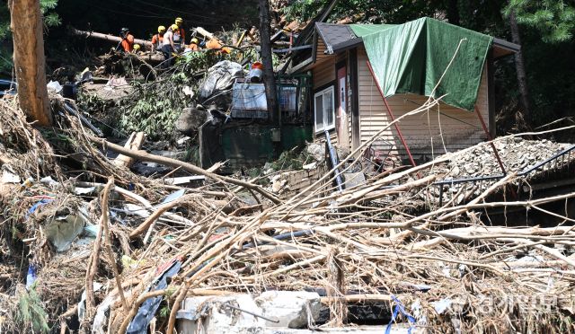 21일 오후 가평군 조종면 마일리의 한 캠핑장에서 구조대원들이 토사와 쓰러진 나무를 하나하나 치우며 산사태로 실종된 어머니와 중학생 아들을 찾고 있다. 전날 새벽 쏟아진 폭우로 토사가 글램핑장을 덮치면서 일가족 4명이 매몰됐고, 이 가운데 10대 아들은 부상을 입고 구조됐으나 40대 아버지는 조종천 하류에서 숨진 채 발견됐다. 중장비 진입이 어려운 현장에서 구조대는 이틀째 수색을 이어가고 있다.조주현기자