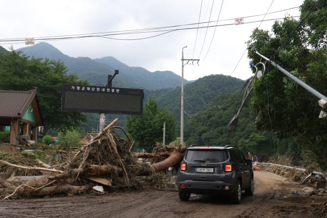 21일 경기도 가평군 대보교 인근 수해 현장에서 꺼진 재난 안내 전광판 아래 나무와 흙더미가 쌓여 있다. 연합뉴스