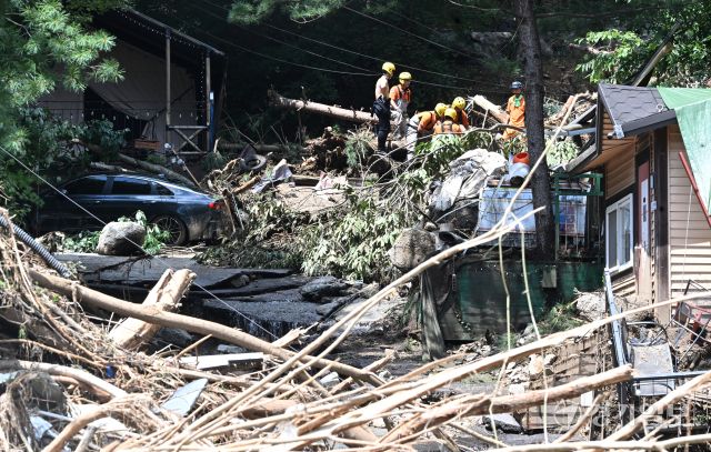 21일 오후 가평군 조종면 마일리의 한 캠핑장에서 구조대원들이 토사와 쓰러진 나무를 하나하나 치우며 산사태로 실종된 어머니와 중학생 아들을 찾고 있다. 전날 새벽 쏟아진 폭우로 토사가 글램핑장을 덮치면서 일가족 4명이 매몰됐고, 이 가운데 10대 아들은 부상을 입고 구조됐으나 40대 아버지는 조종천 하류에서 숨진 채 발견됐다. 중장비 진입이 어려운 현장에서 구조대는 이틀째 수색을 이어가고 있다.조주현기자