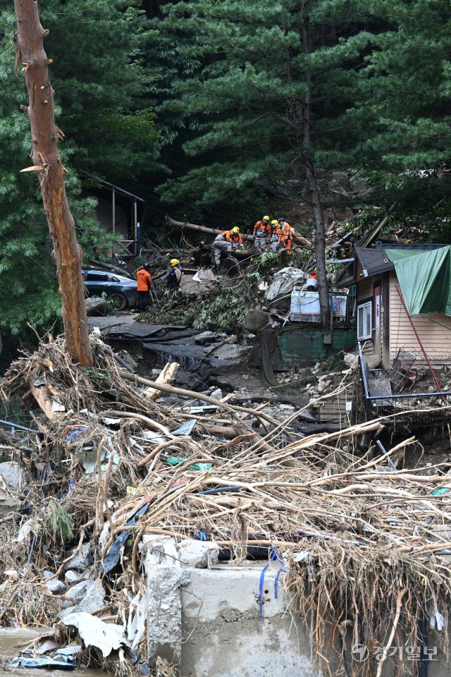 21일 오후 가평군 조종면 마일리의 한 캠핑장에서 구조대원들이 토사와 쓰러진 나무를 하나하나 치우며 산사태로 실종된 어머니와 중학생 아들을 찾고 있다. 전날 새벽 쏟아진 폭우로 토사가 글램핑장을 덮치면서 일가족 4명이 매몰됐고, 이 가운데 10대 아들은 부상을 입고 구조됐으나 40대 아버지는 조종천 하류에서 숨진 채 발견됐다. 중장비 진입이 어려운 현장에서 구조대는 이틀째 수색을 이어가고 있다.조주현기자