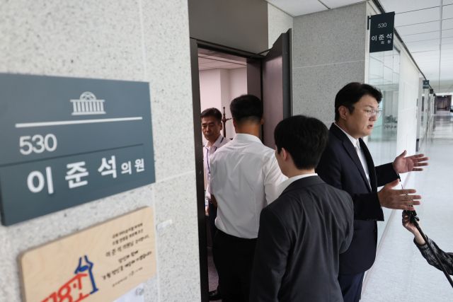 개혁신당 김정철 최고위원이 30일 서울 여의도 국회 의원회관 이준석 의원실 앞에서 ‘김건희특검 관련 압수수색 절차적 문제점 및 준항고 주요 이유 언론 브리핑’을 하는 가운데 특검 관계자들이 압수수색을 위해 의원실로 들어가고 있다. 연합뉴스