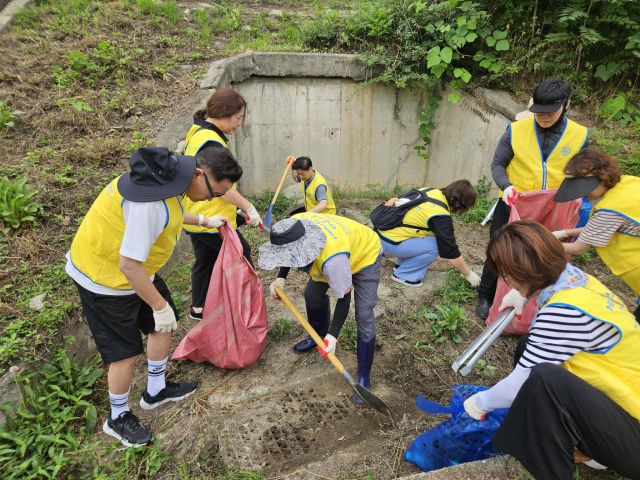 하남시 덕풍천 빗물배수구 오물 등을 제거하고 있는 성도 등 자원봉사자. 하남 하나님의교회 제공