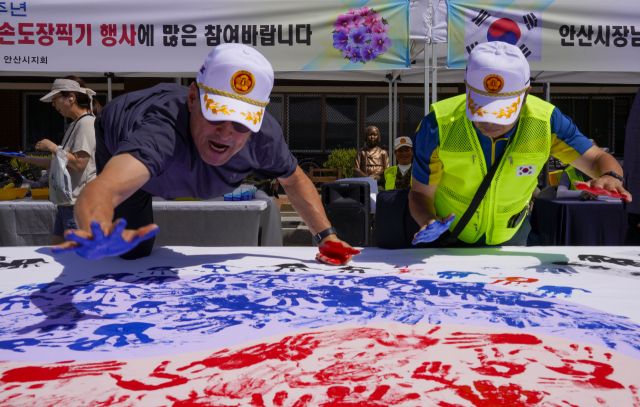 10일 오전 광복 80주년을 맞아 상록수역 손바닥 페인팅 행사에서 광복회 회원들이 태극기에 손도장을 찍고 있다.