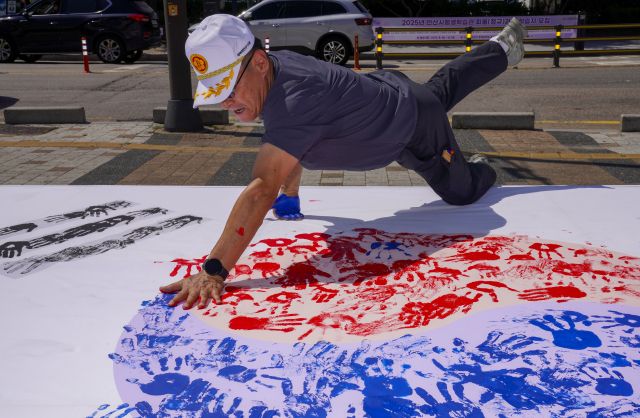 10일 오전 광복 80주년을 맞아 상록수역 손바닥 페인팅 행사에서 광복회 회원이 태극기에 손도장을 찍고 있다.