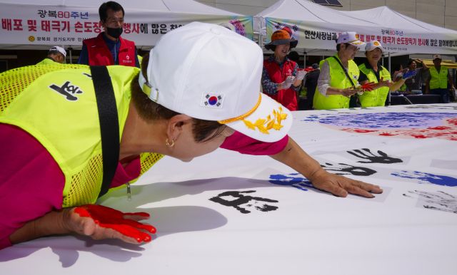 10일 오전 광복 80주년을 맞아 상록수역 손바닥 페인팅 행사에서 광복회 회원들이 태극기에 손도장을 찍고 있다.