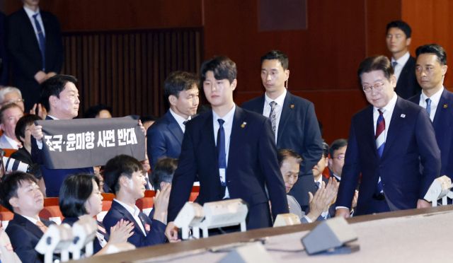 국민의힘 안철수 의원이 15일 서울 세종문화회관에서 열린 80주년 광복절 경축식에서 이재명 대통령이 경축사를 마치고 자리를 향할 때 '조국·윤미향 사면 반대'라는 문구가 적힌 펼침막을 들어보이고 있다. 연합뉴스