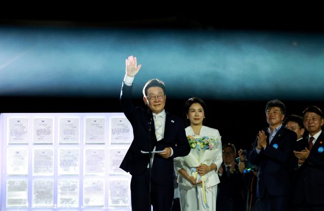 이재명 대통령과 김혜경 여사가 15일 서울 세종대로 광화문광장에서 열린 제21대 대통령 국민임명식 '광복 80년, 국민주권으로 미래를 세우다' 행사에서 '빛의 임명장' 큐브가 완성된 뒤 인사하고 있다. 연합뉴스