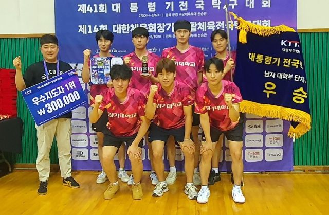 제41회 대통령기 전국탁구대회 남자 대학부 단체전서 8연패의 금자탑을 쌓아올린 경기대 이재욱 감독(왼쪽)과 선수들이 시상식 후 우승기를 앞세우고 기념촬영을 하고 있다.경기대 제공