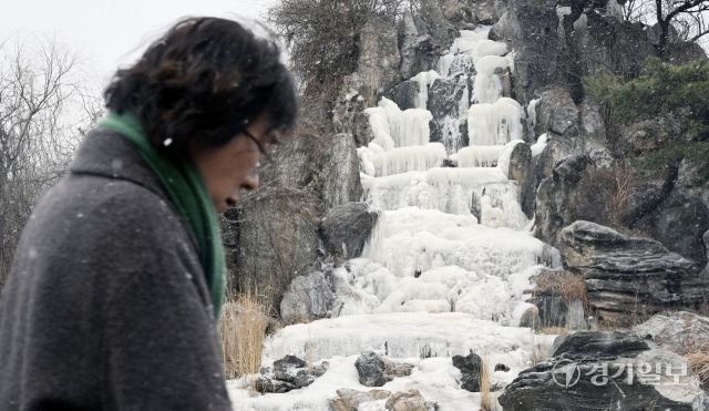 12일 오후 인천 연수구 한 인공폭포에서 시민들이 내리는 눈을 맞으며 발걸음을 재촉하고 있다. 조병석기자