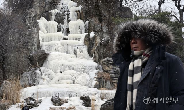 12일 오후 인천 연수구 한 인공폭포에서 시민들이 내리는 눈을 맞으며 발걸음을 재촉하고 있다. 조병석기자