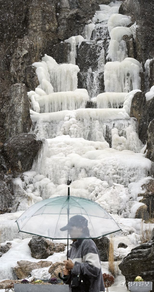 12일 오후 인천 연수구 한 인공폭포에서 시민들이 내리는 눈을 맞으며 발걸음을 재촉하고 있다. 조병석기자