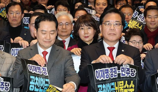 장동혁 대표와 송언석 원내대표를 비롯한 참석자들이 13일 국회에서 열린 국민의힘 국회의원·당협위원장 연석회의 및 의원총회에서 공천 헌금과 뇌물 수수를 규탄하는 구호를 외친 뒤 봉투 모양의 피켓을 찢는 퍼포먼스를 하고 있다. 연합뉴스