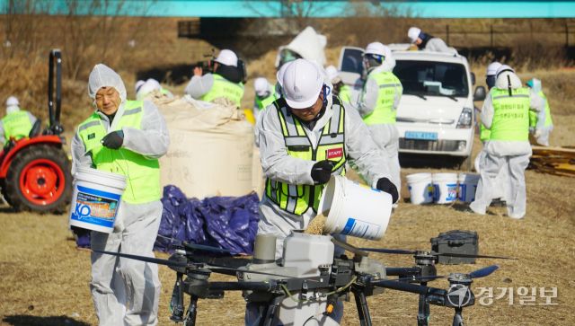 이준석 대장을 비롯한 장항습지 철새 드론급식 봉사대원들이 드론에 볍씨를 채우고 있다. 신진욱기자