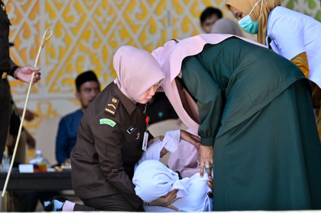A woman faints after being publicly caned by a member of the Sharia police in Banda Aceh on January 29, 2026. (Photo by CHAIDEER MAHYUDDIN / AFP)