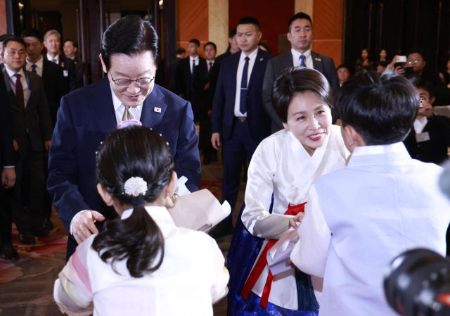 이재명 대통령과 김혜경 여사가 4일 중국 베이징 한 호텔에서 열린 재중 동포 만찬간담회에서 화동으로부터 꽃다발을 받고 있다. 연합뉴스