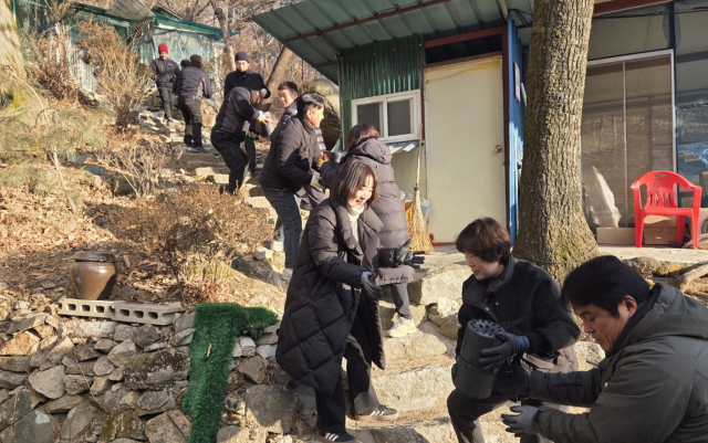 ㈜우리산업 임직원들이 신북면 취약계층에 연탄을 전달하기 위해 가파른 길에 서서 연탄을 나르고 있다. 포천시 제공