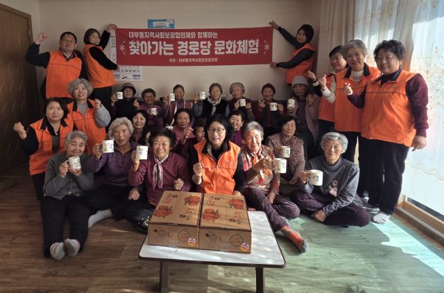 안산 대부동 지사협이 진행한 ‘찾아가는 경로당 문화교실’ 프로그램에 참여한 지역 어르신들이 직접 꾸민 컵을 들고 기념 촬영을 하고 있다. 안산시 제공