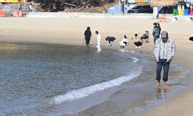 포근한 봄 날씨를 보인 25일 인천 중구 영종도 을왕리 해수욕장을 찾은 한 나들이객들이 바닷물에 발을 담그며 해변을 거닐고 있다.조병석기자