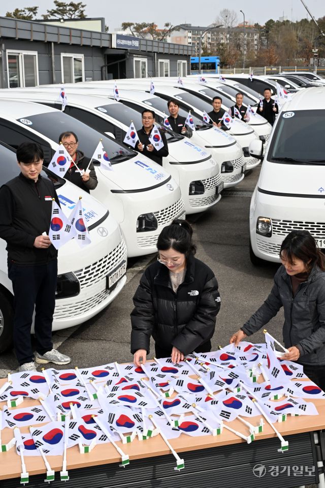3·1절을 사흘 앞둔 26일 오후 수원시교통약자이동지원센터에서 수원도시공사 관계자들이 교통약자이동지원차량인 ‘한아름콜택시’에 태극기를 부착하고 있다. 김시범기자