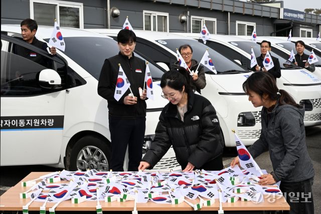 3·1절을 사흘 앞둔 26일 오후 수원시교통약자이동지원센터에서 수원도시공사 관계자들이 교통약자이동지원차량인 ‘한아름콜택시’에 태극기를 부착하고 있다. 김시범기자