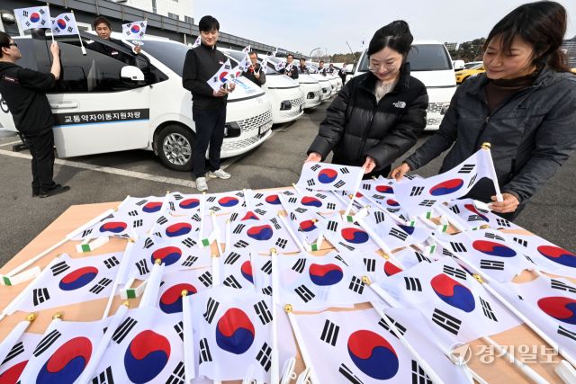 3·1절을 사흘 앞둔 26일 오후 수원시교통약자이동지원센터에서 수원도시공사 관계자들이 교통약자이동지원차량인 ‘한아름콜택시’에 태극기를 부착하고 있다. 김시범기자