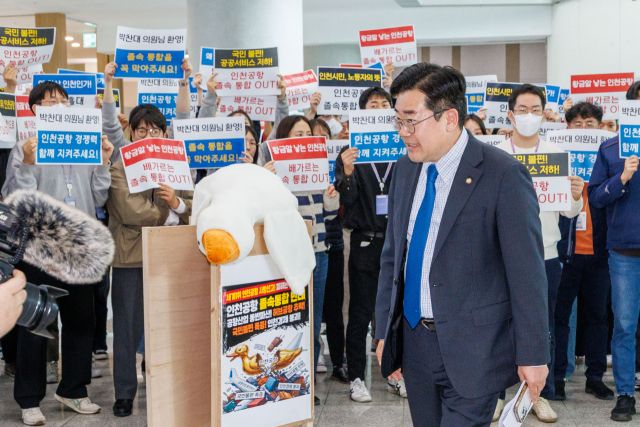 오는 6·3전국동시지방선거에서 더불어민주당 인천시장 후보로 출마한 박찬대 국회의원(연수갑)이 24일 인천국제공항공사 노조와의 간담회를 위해 공항공사에 들어서자 뒷편으로 조합원들이 인천공항 통합 반대 피켓을 들어보이고 있다. 공항공사 제공