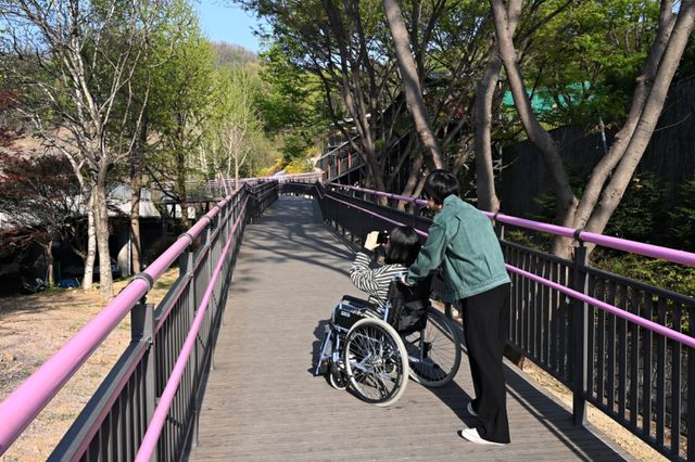 휠체어 이용객이 부천시 무장애 데크길을 이용해 진달래동산으로 이동하고 있다. 부천시 제공