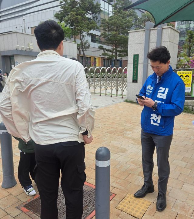 김종천 과천시장 예비후보가 지난 20일 과천 갈현초등학교 정문에서 한 학부모를 만나 교육과 교통문제에 대해 대화를 나누고 있다. 김종천 과천시장 예비후보 선거 캠프 제공