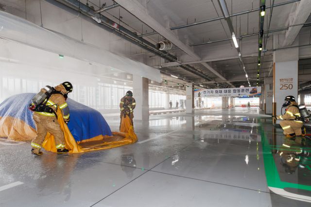 최근 인천국제공항 제2여객터미널 단기주차장에서 열린 ‘전기차 화재 대응 합동훈련’에서 공항소방대원들이 질식소화포를 이용해 전기차 화재를 진압하고 있다. 공항공사 제공