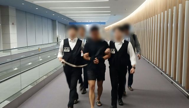 법무부 관계자들이 그룹 방탄소년단(BTS) 정국을 포함한 국내 재력가들의 명의를 도용해 거액을 빼돌린 해킹조직 총책급 범죄인인 중국 국적 전모(34)씨를 인천국제공항을 통해 강제송환하고 있다. 연합뉴스