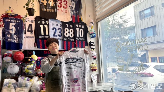 수원특례시 영통구 원천동에서 샌드위치 가게를 운영하는 구본빈씨(37)가 수원FC 유니폼을 들어 보이고 있다. 구씨의 가게는 수원FC ‘우리동네 캐슬클럽’ 제휴 매장으로 샌드위치 1개가 팔릴 때마다 100원씩 구단에 기부하고 있다. 김소현기자