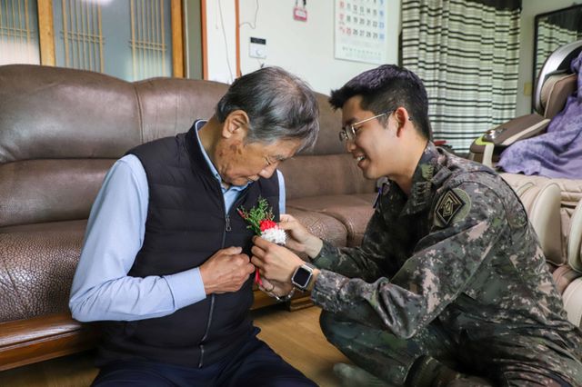 이현수 육군제2기갑여단 기갑수색중대장이 어버이날을 맞아 부대 창설 당시에 복무했던 박종석옹을 방문, 카네이션을 달아 주고 있다. 육군제2기갑여단 제공