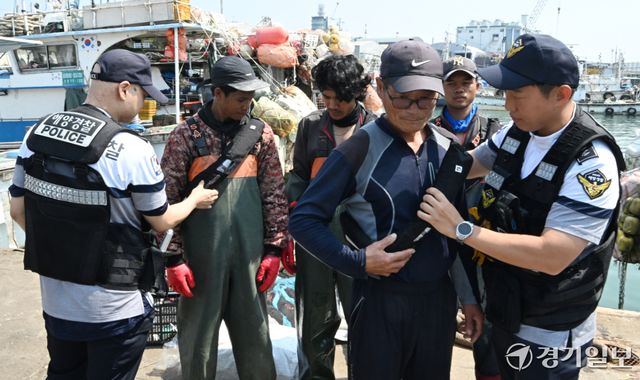 15일 오전 인천 중구 인천항 연안부두에서 인항파출소 해양경찰이 조업을 나가는 어선원들에게 구명조끼 착용 의무화를 안내하고 있다. 오늘 7월 1일부터 일부 어선에 한정됐던 구명조끼 착용 의무를 확대해 승선 인원수와 관계없이 모든 어선원이 외부에 노출된 갑판에서 작업하거나 이동할 때 반드시 구명조끼를 착용하도록 한다.조병석기자