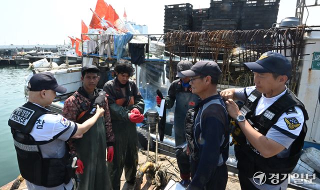 15일 오전 인천 중구 인천항 연안부두에서 인항파출소 해양경찰이 조업을 나가는 어선원들에게 구명조끼 착용 의무화를 안내하고 있다. 오늘 7월 1일부터 일부 어선에 한정됐던 구명조끼 착용 의무를 확대해 승선 인원수와 관계없이 모든 어선원이 외부에 노출된 갑판에서 작업하거나 이동할 때 반드시 구명조끼를 착용하도록 한다.조병석기자