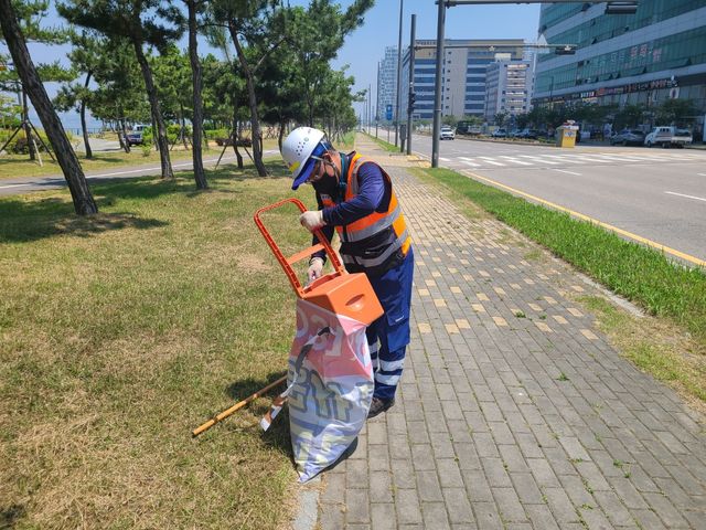 보도자료6 환경미화원이 폐현수막을 재활용한 마대를 이용해 가로청소를 하고 있다