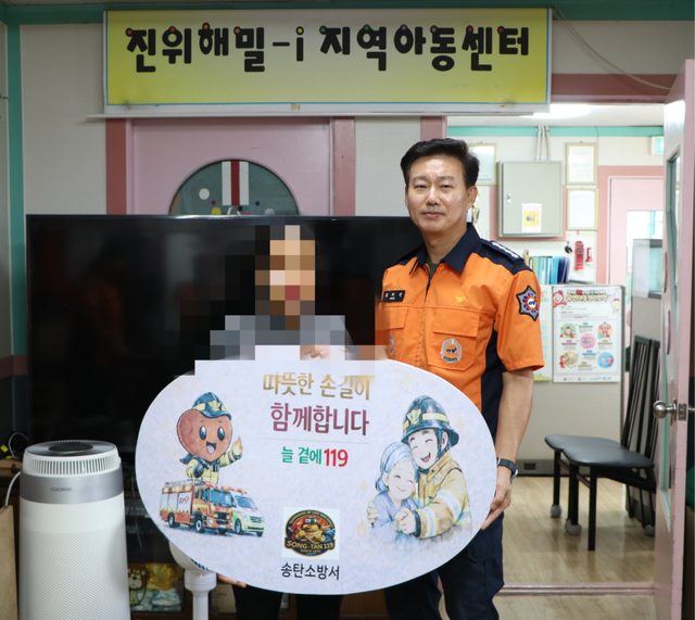 17일 홍의선 송탄소방서장이 평택시 진위면 진위해밀-i지역아동센터에서 열린 ‘따뜻한 동행 경기119’ 사업 생활안정지원금 전달식에서 수혜자로 선정된 다문화가정 A씨와 기념촬영을 하고 있다. 송탄소방서 제공