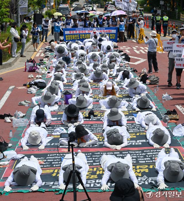 18일 오전 경기도청 2번 게이트 앞에서 전국장애인부모연대 경기지부 회원들이 발달 장애인에 대한 의료 및 재활 인프라에 대한 구축 등을 요구하며 오체투지를 하고 있다. 윤원규기자