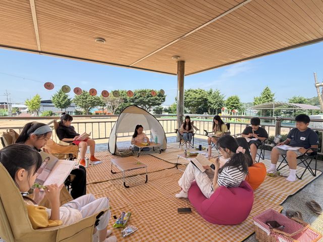 교사와 학생들이 학교 운동장에 마련된 구령대에서 선생님과 독서를 즐기고 있다. 김포교육지원청 제공