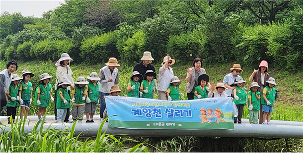 사우시립어린이집 원아와 교사, 사우동 주민자치회 위원들이 계양천에 EM흙공을 던지며 하천정화 활동을 하고 있다. 사우동 행정복지센터 제공