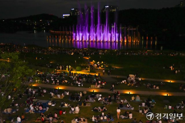 낮 기온이 30도를 웃도는 무더운 날씨가 이어지면서 해가 진 뒤 야외 활동에 나서는 시민들이 늘고 있다. 27일 저녁 화성특례시 동탄호수공원을 찾은 시민들이 화려한 동탄루나쇼를 관람하며 주말 여름밤을 즐기고 있다.