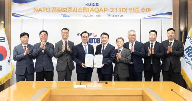 이용배 현대로템 사장(왼쪽 네 번째)과 신상범 기품원장(왼쪽 다섯 번째) 등 관계자들이 현대로템 의왕 본사에서 나토 품질보증시스템 인증 수여식을 마친 뒤 기념촬영을 하고 있다. 현대로템 제공