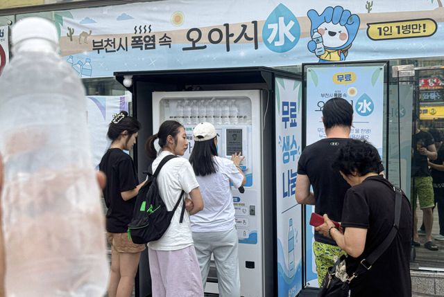 지난 26일 부천역 마루광장에 설치된 ‘폭염 속 오아시水’ AI 생수자판기에서 시민들이 ARS 본인인증을 거쳐 무료 생수를 받고 있다. 경기일보 DB