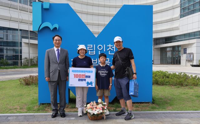 우동식 국립인천해양박물관장(왼쪽)이 28일 오전 박물관 앞에서 100만번째 관람객에게 축하 꽃다발을 건네고 기념사진을 촬영하고 있다. 박물관 제공