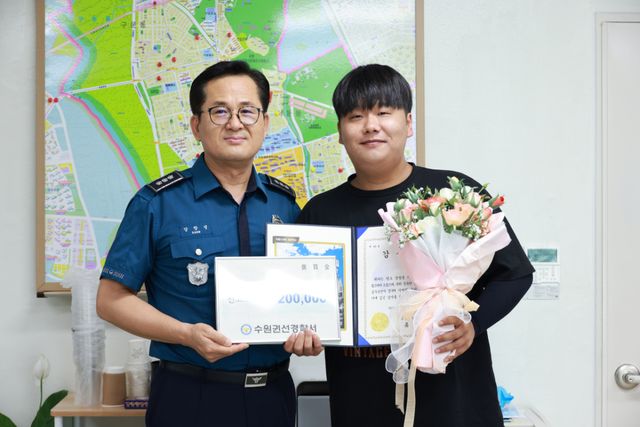 음주운전 의심 차량을 신고해 경찰과 함께 검거한 최민규씨(오른쪽)가 강창성 수원 서호지구대 대장으로부터 감사장과 꽃다발을 전달받고 있다. 본인 제공