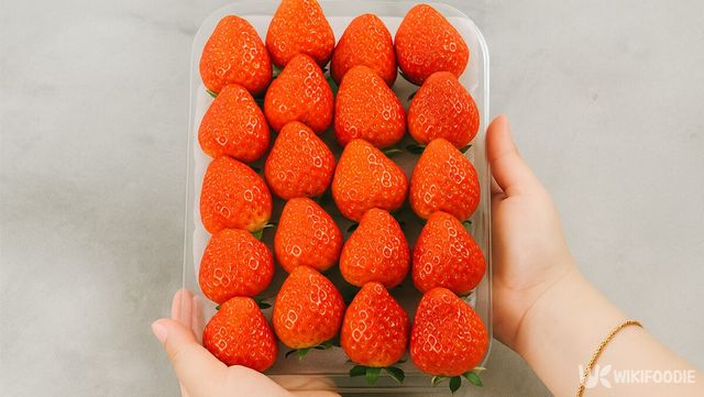 투명 용기에 담긴 잘 익은 딸기를 들어 올리고 있다. / 위키푸디