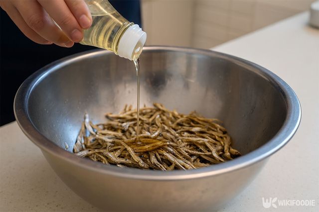 볶아낸 멸치에 참기름을 넣고 있다. / 위키푸디