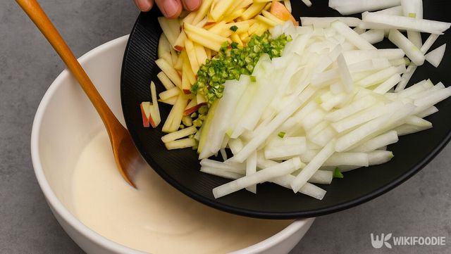 채 썬 무와 사과, 고추를 반죽 그릇에 함께 붓고 있다. / 위키푸디