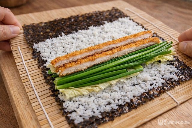 김밥 발 위에 돈가스와 각종 채소를 올려 돈가스 김밥을 만드는 모습이다. / 위키푸디