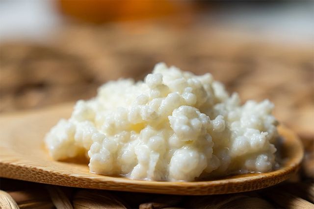 나무 숟가락에 담긴 케피어 곡물과 발효된 케피어 음료가 함께 놓여 있다. / Dulcemarina-shutterstock.com