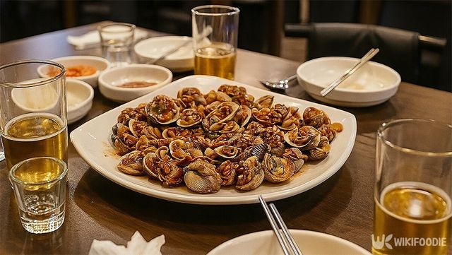 맥주잔들과 꼬막 무침이 식당 식탁에 놓여 있다. / 위키푸디